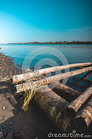 A broken bamboo canoe stranded on the edge of the lake Stock Photo