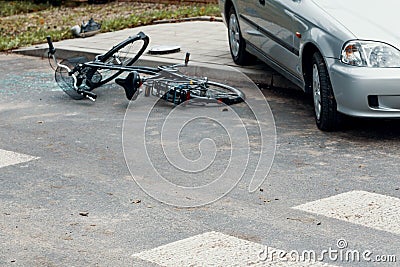 Broken bicycle and car on the road after dangerous collision Stock Photo