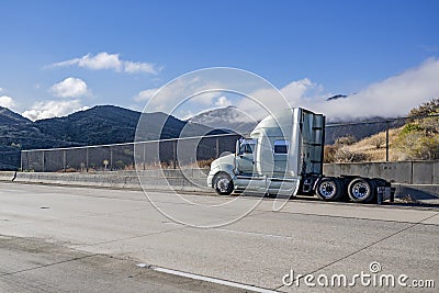 Broken big rig semi truck without of the semi trailer stands on the shoulder side of the road waiting for the mobile towing road Stock Photo