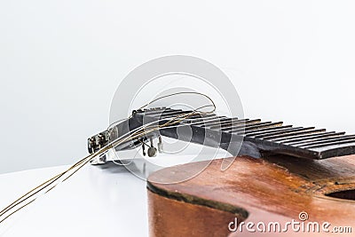 Broken brown classical guitar with detached bridge from body isolated Stock Photo