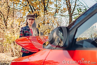 Broken car. Young woman opening hood of her auto that stopped on road outdoors. Breakage Stock Photo