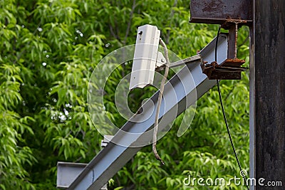 Broken CCTV camera. Broken cable. Security breach. Abandoned security camera on the background of trees. Damaged Stock Photo