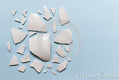 Broken ceramic porcelain pieces on blue background Stock Photo