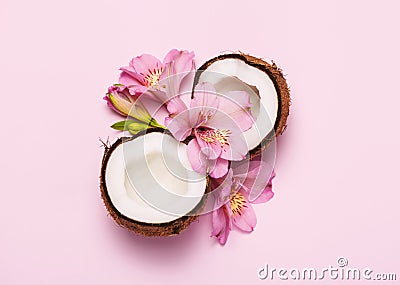 Broken coconut with tropic flowers on pink background Stock Photo