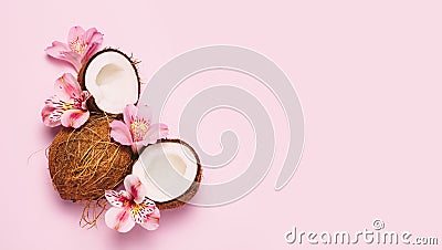 Broken coconut with tropic flowers on pink background Stock Photo