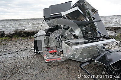 Broken computer parts, monitors and printers in front of nature landscape with a river background. Discarded electronic Stock Photo