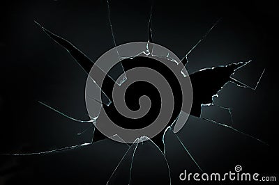 Broken cracked glass with big hole over black background Stock Photo