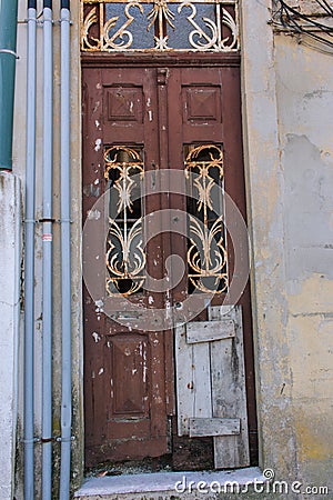 Broken dirty door in abandoned house. Damaged entrance to old building. Closed vintage doorway. Retro exterior. Stock Photo