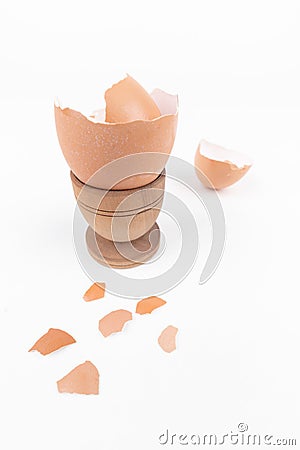 Broken egg shell in old wooden eg stand and scattered across white surface. Minimalism. Animal product concept. Simple breakfast. Stock Photo