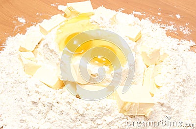 Broken eggs in flour and cube of margarine lying on table Stock Photo