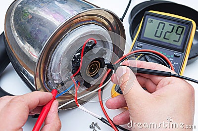 Broken kettle, concept. Person's hands repairing electric kettle with multimeter. Stock Photo