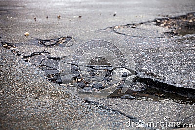 Broken pavement and pothole asphalt road after winter. Stock Photo