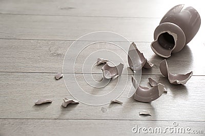 Broken pink ceramic vase on wooden floor Stock Photo