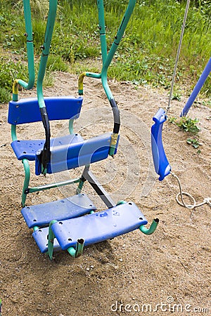 Broken plastic children`s swing in a playground, painted, welding on metal, so as not to break, old and unsafe swings Stock Photo