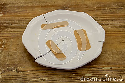 Broken plate fixed with bandaid strips Stock Photo