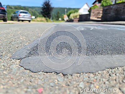 Broken road and repairs on a road with holes in the asphalt Stock Photo