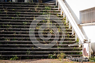 Broken stairs with special lifting platform for wheelchair users, at the entrance to abandoned building showing rust and decay Stock Photo