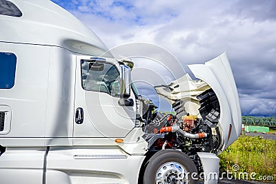 Broken white big rig semi truck tractor stands on the side of the road with an open hood awaiting mobile repair assistance Stock Photo