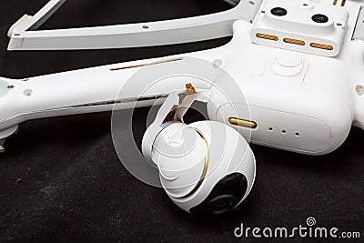 Broken white drone after a fall. Isolated on a black background. Damaged body and stabilizer camera gimbal. Plugged cable loop Stock Photo