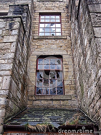 Broken windows in an empty abandoned vandalized old building Stock Photo