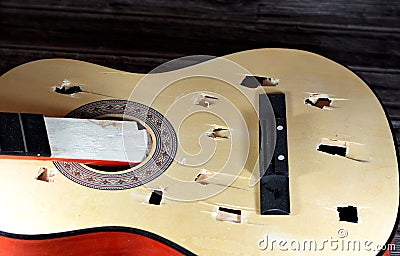 A broken wooden old classic guitar with damaged strings chords, shattered musical instrument, unattached damaged guitar with cut Stock Photo