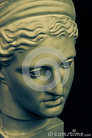 Plaster sculpture of woman face. Bronze color gypsum copy of ancient statue of Diana head for artists on black Stock Photo