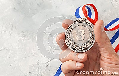 Bronze medal. A man holds a third place award with a ribbon in his hand Stock Photo