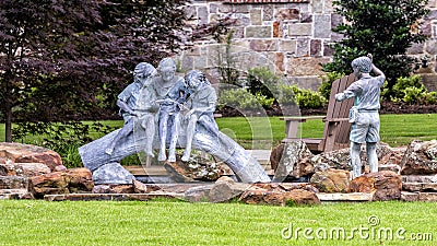 Bronze sculpture of three girls sitting on a log fishing on a lawn in Dallas, Texas. Editorial Stock Photo