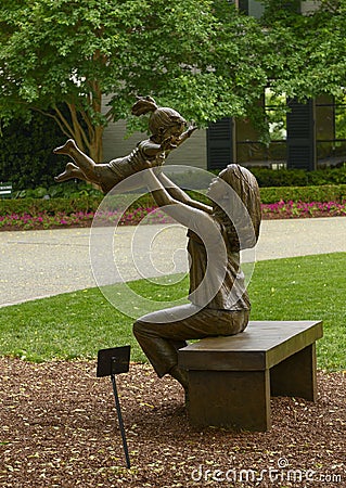 Bronze sculpture of woman holding up a happy child by Gary Price at the Dallas Arboretum and Botanical Garden Editorial Stock Photo