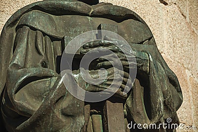 Bronze statue detail of priest hands holding a cross at Caceres Stock Photo