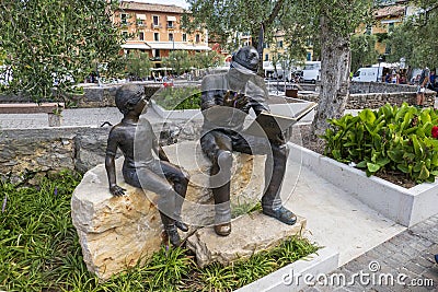 Bronze statue, soldier reading boy from book, in Torri del Benaco Editorial Stock Photo