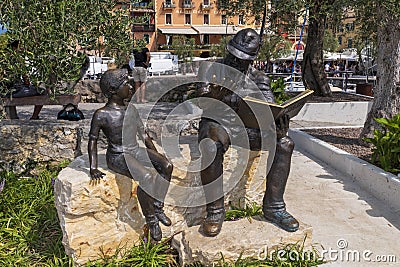 Bronze statue, soldier reading boy from book, in Torri del Benaco Editorial Stock Photo