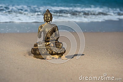 Bronze statuette Buddha on the beach with waves Stock Photo