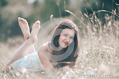 Brooding young woman lying on grass on summer day. Stock Photo