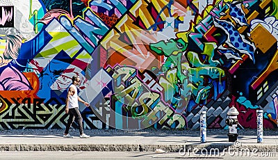 BROOKLYN, NYC, US, October 1 2013: Street art in Brooklyn. Hipster male walking next to a wall of graffiti in Brooklyn, New Editorial Stock Photo