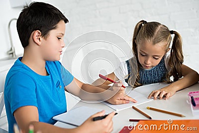 brother and sister doing homework together at table Stock Photo