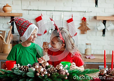 Brother and sister, little boy and girl eating Christmas cookies and drinking drink in Christmas decorations in the kitchen Stock Photo