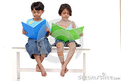 Brother and sister reading books on bench Stock Photo