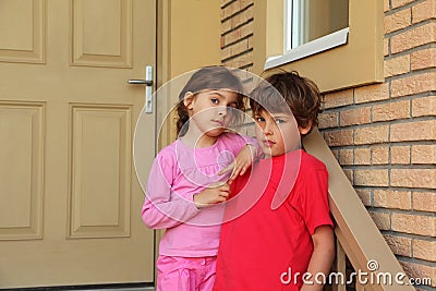 Brother and sister stand near door of cottage Stock Photo