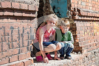 Brother and sister were left alone as a result of military conflicts and natural disasters. Children in a ruined and abandoned Stock Photo