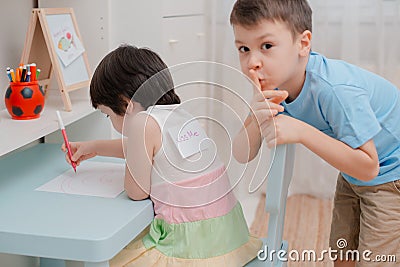 Brother sticks a paper fish to the back of the sisters on April fool`s Day. Children`s humor on April 1. Jokes and fun Stock Photo