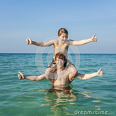 Brothers enjoying the clear warm water at the beautiful beach and playing pickaback Stock Photo
