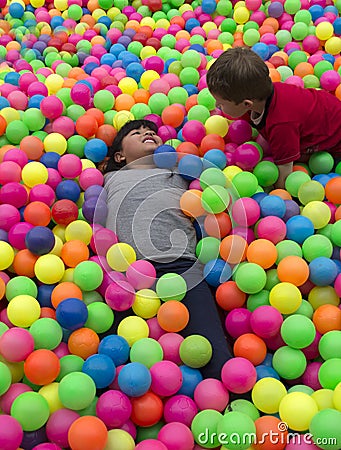 Brothers lays on the big heap of multicolored small balls. Stock Photo