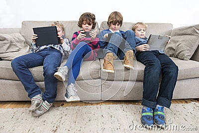 Brothers And Sister Using Technologies On Sofa Stock Photo