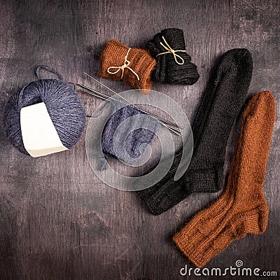 Brown and black knitted socks, gray ball of yarn and knitting on a black and gray wooden background Stock Photo