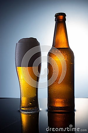 brown bottle of beer poured into a glass of foamy beer, on a water background Stock Photo