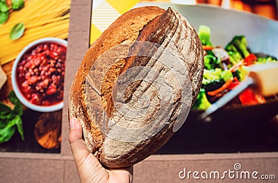 Brown bread in hand of customer near city supermarket wall Stock Photo