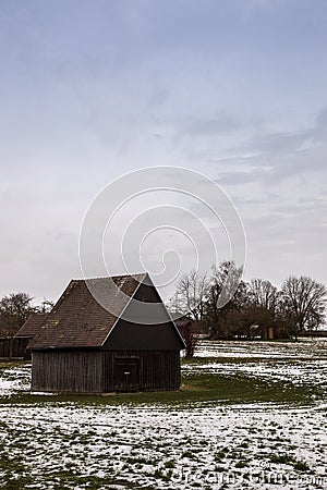 Brown cabin on the icy green field in winter Stock Photo
