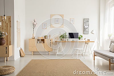 Brown carpet between pouf and grey sofa in white home office int Stock Photo