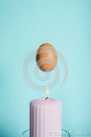 Brown chicken egg with a pink burning candle Stock Photo